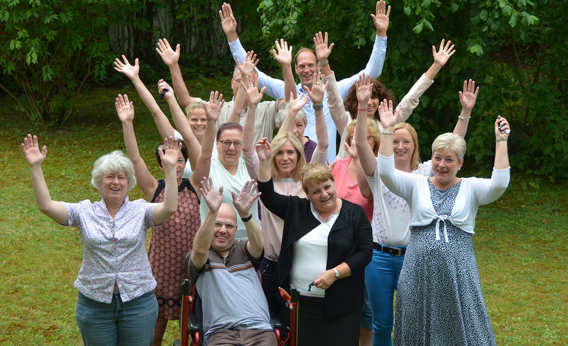 Gruppenfoto der Mitarbeiterinnen und Mitarbeiter, die alle die Arme in die Luft reißen und sich freuen.